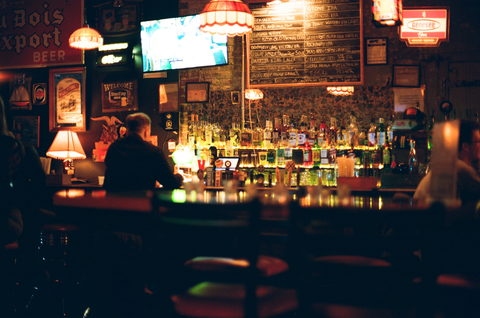 Man sits alone at a colorful bar